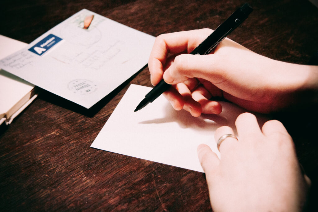 Hands over paper with pen, beginning to write to a pen pal.