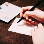 Hands over paper with pen, beginning to write to a pen pal.